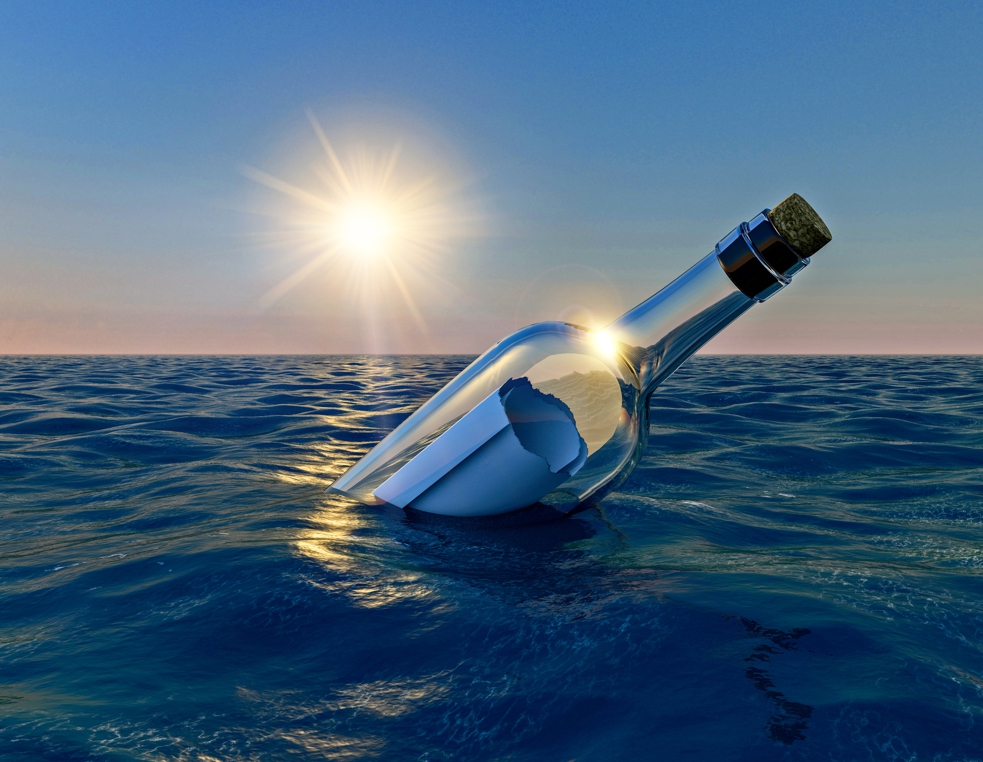 Stylised image of an empty, corked, clear glass bottle with a furled piece of slightly ragged paper in it, floating on a calm sea just before sunset. The pale sun strikes glints across the gentle, blue-green waves and the shoulder of the bottle. There is no land or clouds in sight.